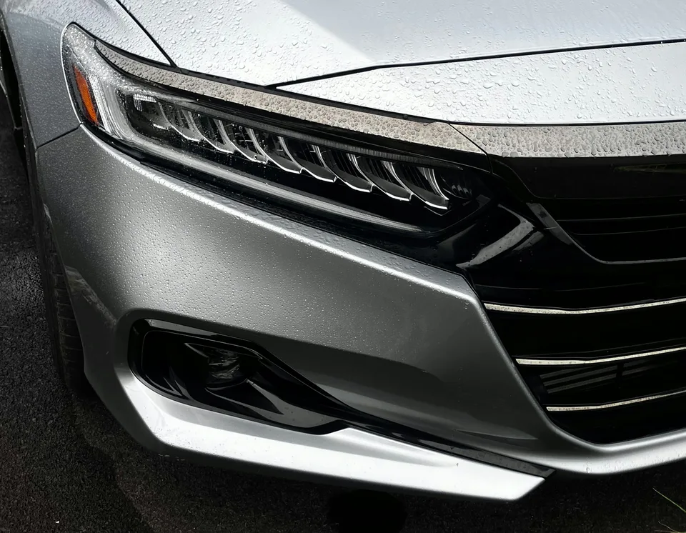 Close-up of a silver car's headlight and grille